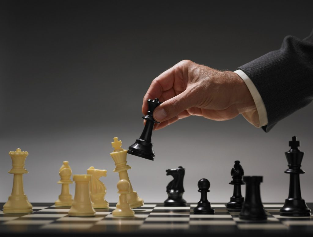 Close-up of a hand moving a chess piece, symbolizing strategic technology leadership and smart decision-making.